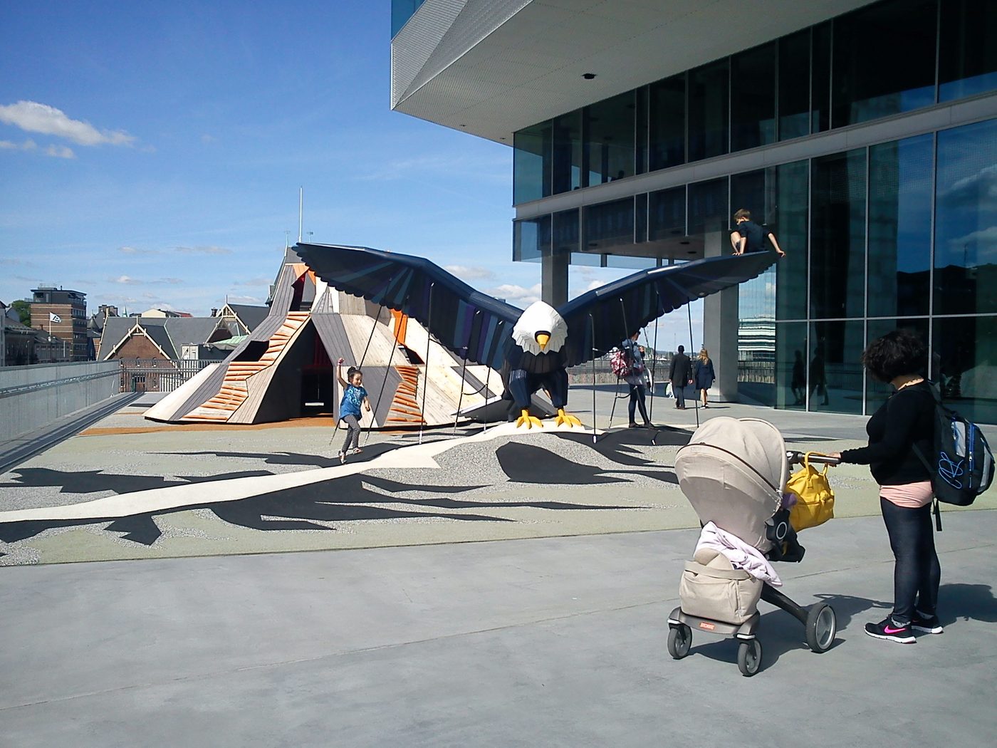A giant timber eagle with outstretched wings beside a wooden nest structure outside a public library