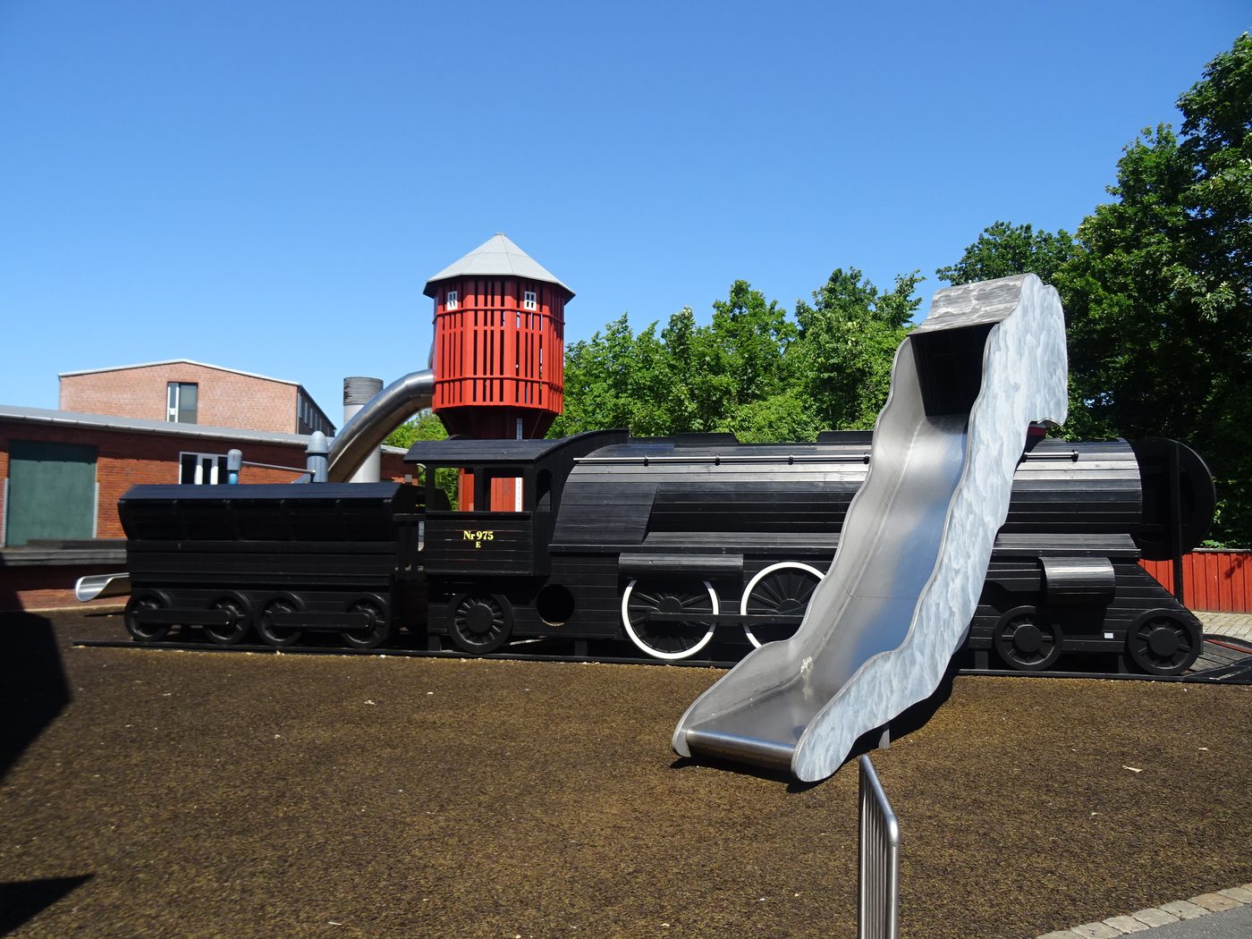 A full-size black wooden steam locomotive playground with a slide and a red water tower